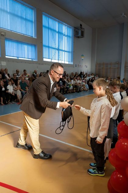 Mężczyzna wręczający uczniowi wyprawkę