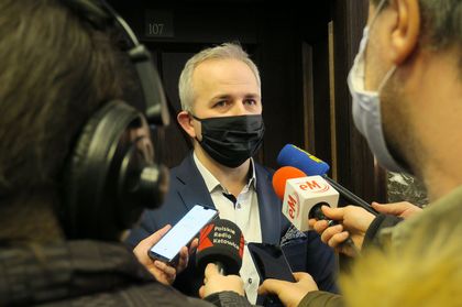 Mężczyna mówiący do kilku mikrofonów dzienikarzy z radia i telewizji