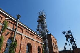 Zabytkowa kopalnia - fragment ceglanego budynku, w tle dwa szyby