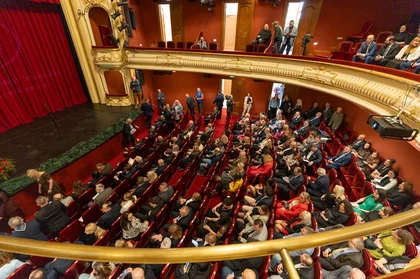 Zdjęcie sali w operze. Na widowni siedzą ludzie.