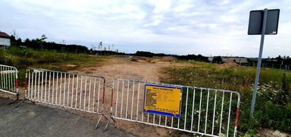 Roboty ziemne przy węźle drogowym, barierki i tablica informacyjna.