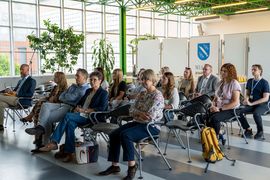 Zdjęcie przedstawia grupę osób siedzących na konferencji.
