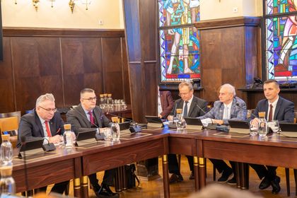 Grupa ludzi siedzących przy stole na spotkaniu w sali w urzędzie miasta.