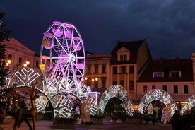 Świątecznie ustrojony rynek nocą, w tle koło widokowe