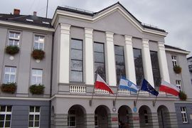 Budynek urzędu miasta, na którym powiewają cztery flagi 