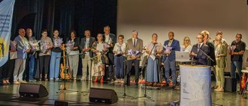 zdjęcie przedstawia ludzi na scenie trzymających kwiaty
