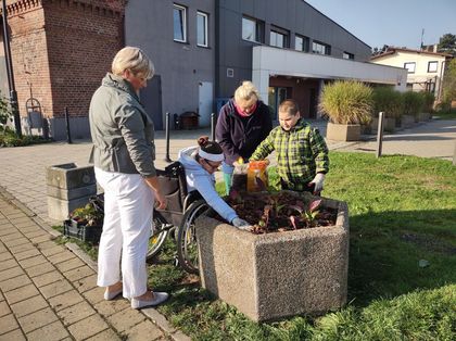 Grupa uczniów sadzi kwiaty z pracownikami Zarządu Zieleni Miejskiej 