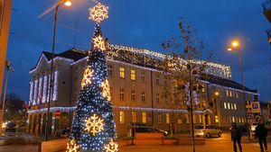 Wieczór. Świątecznie udekorowane miasto - lampki nad ulicami, choinki, i inne ozdoby.
