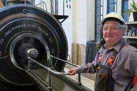 Zabytkowa kopalnia - elementy dawnej parowej maszyny wyciągowej szybu. Obok maszyny starszy mężczyna w kasku