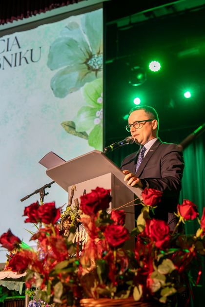 Mężczyzna stoi na scenie i mówi do mikrofonu.