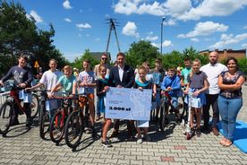 Grupa uczniów na rowerach i hulajnogach na placu szkolnym. Z nimi prezydent Rybnika Piotr Kuczera