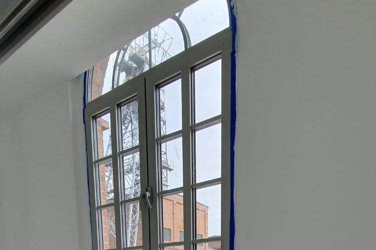 Ignacy 05 2020 12 Ściana z oknem, przez które widać szyb kopalniany.