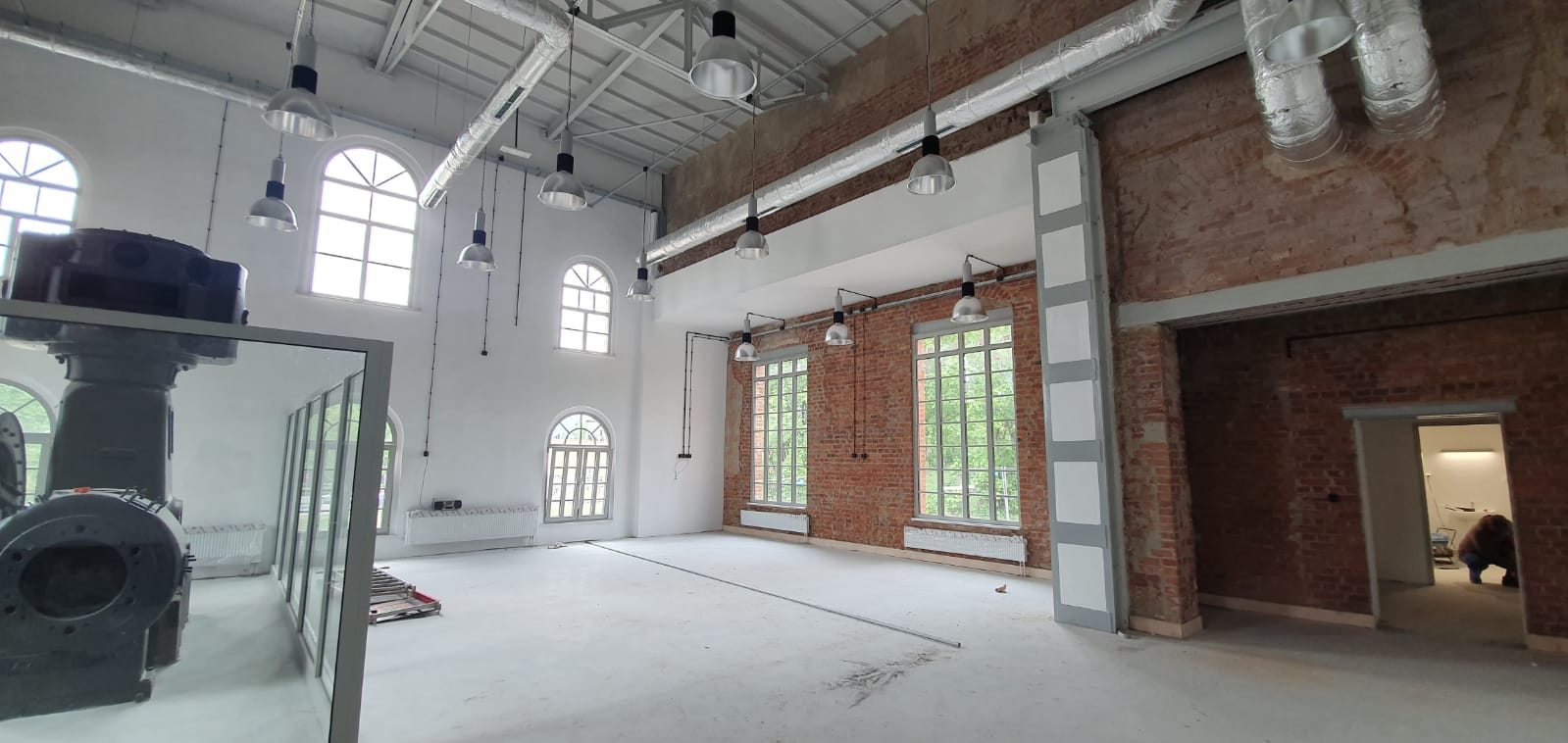 Ignacy 05 2020 2 Industrialne wnętrze, ściany z czerwonej cegły, stalowe konstrukcje. Część ścian otynkowanych na biało, za płytami pleksi ekspozycja - maszyna górnicza.