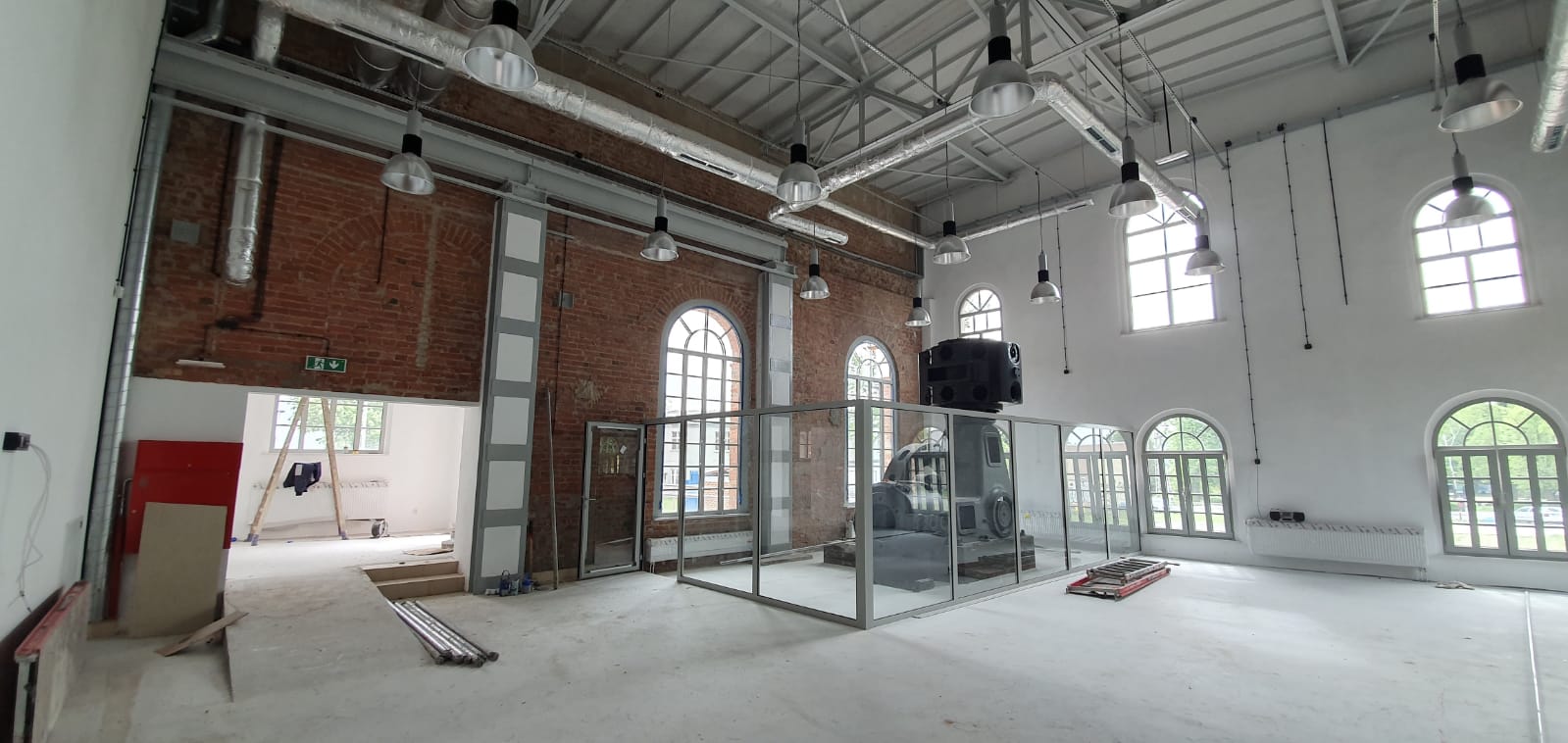 Ignacy 05 2020 3 Industrialne wnętrze, ściany z czerwonej cegły, stalowe konstrukcje. Część ścian otynkowanych na biało, za płytami pleksi ekspozycja - maszyna górnicza.