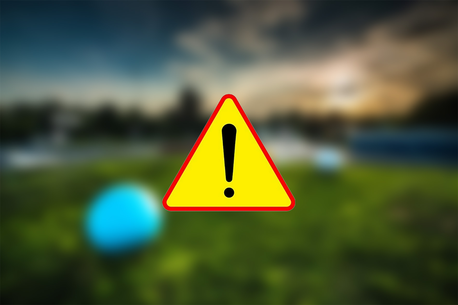 Znak drogowy - wykrzyknik na tle żółtego trójkąta. Na drugim planie rondo drogowe.